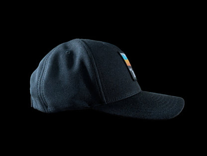 The Sòlas Cap. Black outdoor performance cap with a colorful landscape and An Turas™ logo on a woven patch. Profile view.